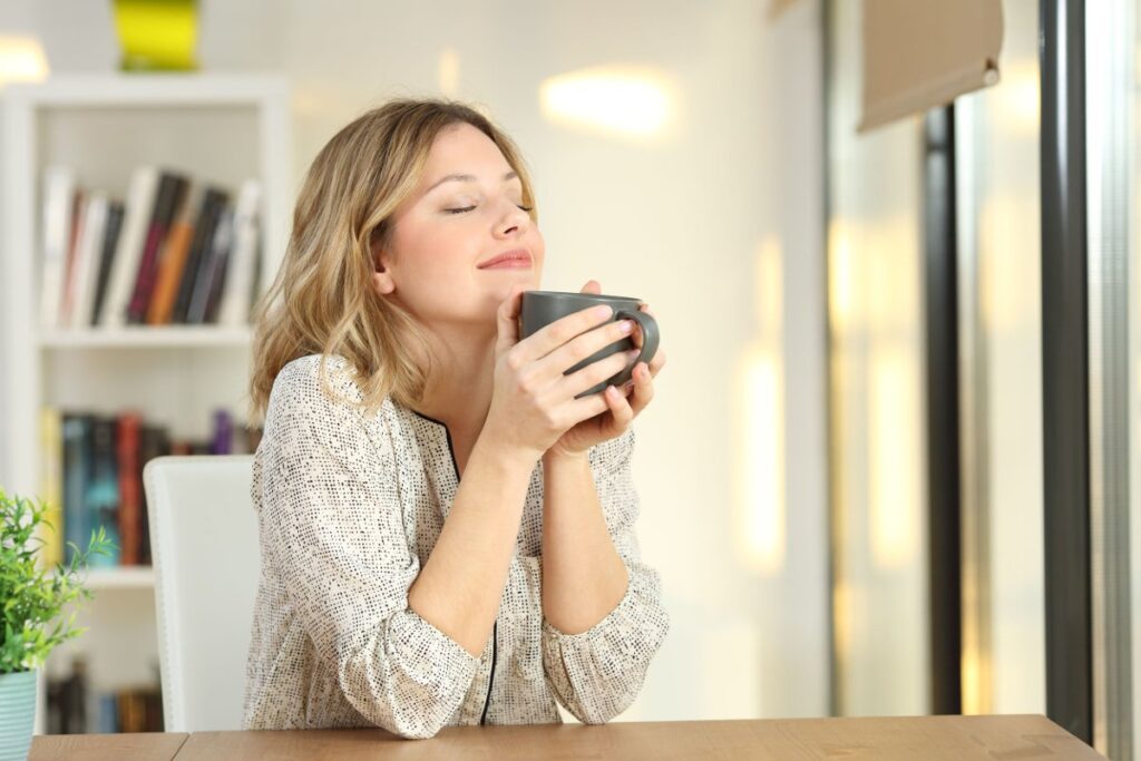 a girl smelling fresh air in her home and have a coffee mug in her hand.