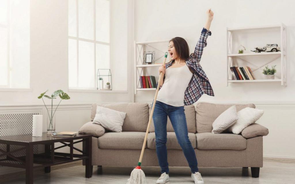 a girl in her home with a mop and she is dancing, seems like she successfully cleaned her house and got rid of all the cigarette smoke odors from her home.