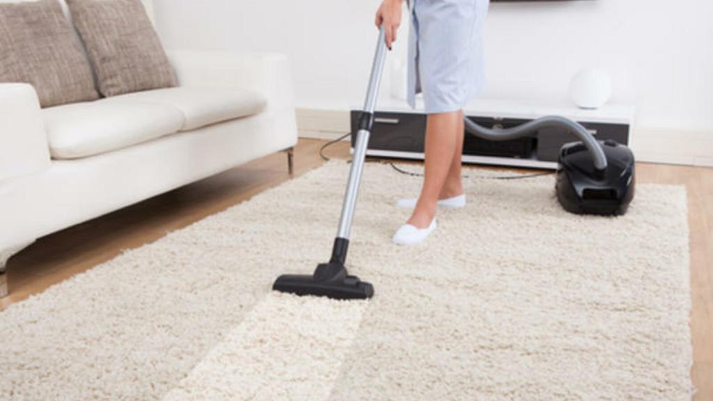a women is cleaning carpet with a vacuum cleaner.