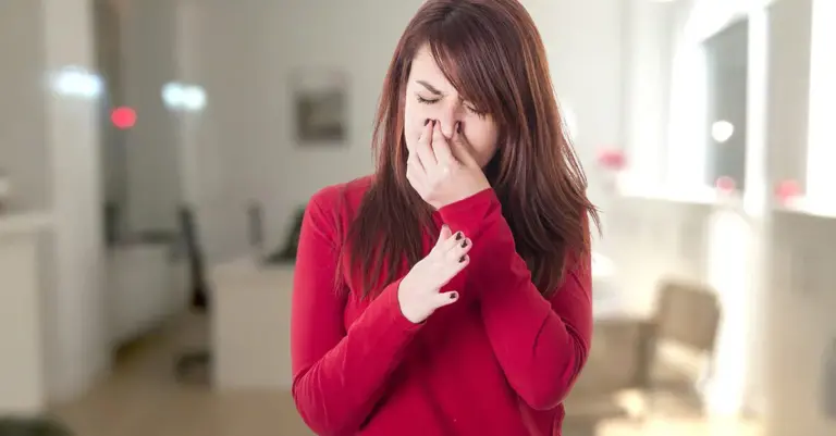 girl hand on her nose because she is feeling odor.
