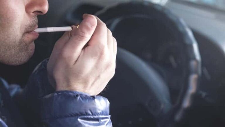 a man lighting cigarette in car